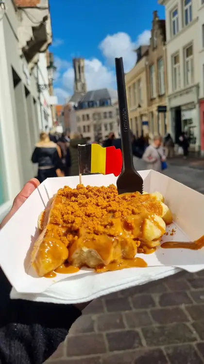 Un waffle belga en una calle de Brujas, con el campanario al fondo