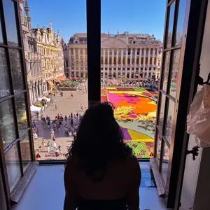 Mishell en una ventana sobre la alfombra de flores de la Grand-Place de Bruselas