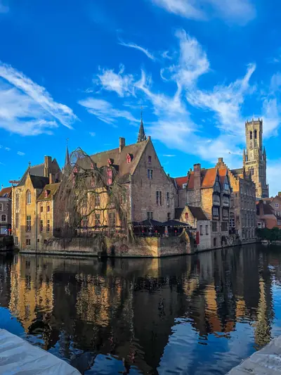 El Rozenhoedkaai de Brujas reflejado en el canal, con el campanario al fondo